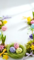 Easter nest with colorful speckled eggs surrounded by spring flowers and decorations on white background for holiday greeting cards and seasonal designs.