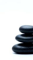 Stacked smooth dark stones with water droplets on white background, suitable for spa, wellness, meditation and relaxation therapy concepts.
