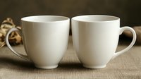 Two elegant white porcelain coffee cups on natural linen tablecloth with soft bokeh background, minimalist composition for cafe and restaurant design.