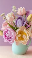 Spring bouquet with peonies, tulips, and wildflowers in mint ceramic pitcher against soft purple background. Perfect for seasonal greeting cards.