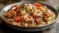 Grilled shrimp pasta with cherry tomatoes and herbs served in rustic skillet, garnished with fresh parsley for restaurant menu or cooking blog content.