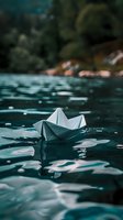 White paper boat floating on dark turquoise water surface with bokeh reflections and ripples, creating dreamy atmospheric scene for concepts of journey and hope.