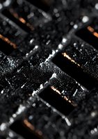 Wet computer keyboard with water droplets in macro shot, dramatic lighting with orange reflections highlighting black keys. For technology and computing concepts.