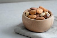 Mixed nuts in wooden bowl on linen napkin featuring almonds, walnuts, hazelnuts and Brazil nuts for healthy snacking and cooking ingredients.
