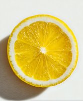 Fresh yellow lemon slice on white background showing juicy pulp and natural texture with dramatic shadow, macro photography for food and beverage industry.