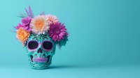 Decorative turquoise sugar skull adorned with vibrant fresh flowers including pink, purple and orange gerbera daisies against blue background, Day of Dead concept.