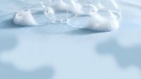 Clear glass bubbles scattered on soft blue surface with shallow depth of field, suitable for abstract backgrounds and design projects.