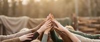 Diverse group of people joining hands together in circle outdoors, showing unity, teamwork and collaboration for community support or corporate team building activities.