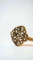Ornate golden vintage key with intricate baroque scrollwork and decorative patterns isolated on white background for luxury design projects.