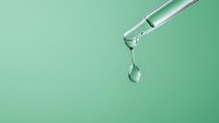 Clear liquid drop falling from glass dropper against mint green background, capturing moment of separation with crystal clarity and pure reflection.