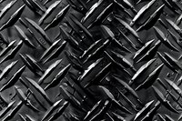 Black metallic diamond plate pattern with industrial tread surface texture creates dramatic light and shadow effect, suitable for backgrounds and design elements.