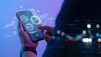 Hand holding smartphone displaying digital interface with glowing data visualization elements against blurred city lights background at night.
