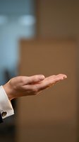 Open palm of a man in formal white shirt showing empty hand gesture for offering, presenting, or giving concept in business environment.
