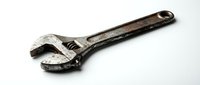 Old rusty adjustable wrench tool isolated on white background for repair maintenance and mechanical work projects.