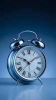 Classic chrome alarm clock with Roman numerals on blue gradient background for time management and punctuality concepts.
