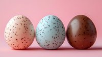 Speckled quail eggs in white, blue, and brown arranged in row on pink background, creating minimalist composition for food styling and Easter designs.