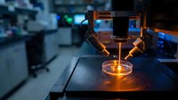 Scientific microscope with glowing orange specimen sample in modern laboratory research facility for medical analysis and biotechnology experiments.