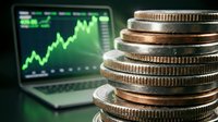 Stacked coins with upward trending stock market chart on laptop screen, representing financial growth, investment returns, and wealth accumulation for business concepts.