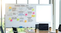 Modern office workspace with business trends 2027 whiteboard featuring colorful sticky notes, charts and strategic planning elements for corporate presentations.