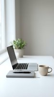 Minimalist home office workspace with laptop, coffee cup, notebook and plant on white desk near window for remote work and productivity.