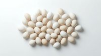 White and beige oval pills scattered on clean surface for pharmaceutical medical healthcare concept isolated on white background.