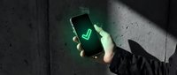 Person holding smartphone displaying glowing green checkmark symbol on dark concrete background, representing approval, success, verification, and digital confirmation for business and technology concepts.
