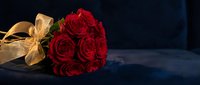 Elegant red roses bouquet with golden ribbon on dark blue velvet surface for romantic occasions, Valentine's Day, anniversary celebrations and luxury gifts.