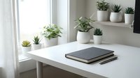 Minimalist home office workspace with succulent plants in white pots on floating shelves and closed notebook on clean white desk near bright window.