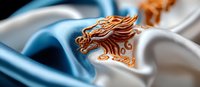 Elegant copper phoenix emblem on flowing blue and white silk fabric background creates luxurious branding design element with dramatic lighting and shadows.