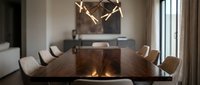 Luxurious dining room with wooden table, upholstered chairs, and modern antler chandelier overhead, suitable for interior design and home decor projects.