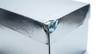 Melting ice cube with water droplet forming at corner showing phase transition from solid to liquid state for science education and climate concepts.