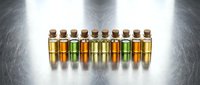 Assorted essential oils and aromatherapy liquids in glass bottles with cork stoppers arranged in a row on reflective surface for wellness and spa applications.