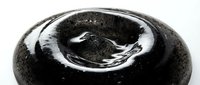 Macro shot of water droplet on dark stone surface with ripple effect and reflection, isolated on white background for design use.
