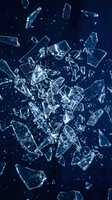 Shattered glass fragments exploding with dynamic motion against dark blue background. Sharp crystalline pieces scatter in dramatic destruction pattern.