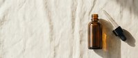 Amber glass dropper bottle with pipette on natural linen fabric background, suitable for essential oils, serums, and cosmetic packaging design.