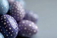 Decorative Easter eggs in soft blue and purple colors with polka dot pattern against blurred background, creating festive spring holiday atmosphere.