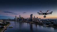 Professional drone flying over modern city skyline at sunset with river and urban landscape aerial photography for commercial technology projects.