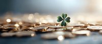 Green four leaf clover on scattered gold coins with soft bokeh background, symbolizing luck, fortune and prosperity in business and financial success.