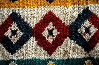 Cozy knitted pattern with geometric diamond shapes in red, navy blue and white wool creating traditional Nordic style winter design. Macro textile texture.