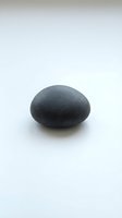 Smooth dark gray stone pebble isolated on white background, suitable for wellness, spa, meditation, and design projects.
