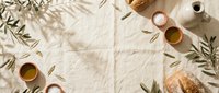 Overhead flat lay of olive branches, golden oil in glass bowls, and artisan bread on natural linen fabric, perfect for culinary, food styling, and Mediterranean lifestyle content.