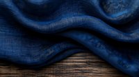 Navy blue linen fabric with natural folds and texture on wooden surface creates elegant backdrop for product photography and design projects.