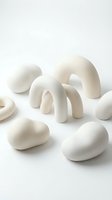White ceramic abstract sculptural forms with smooth curved shapes arranged on neutral background for contemporary art and design projects.