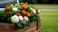 Fresh floral arrangement with orange roses and white hydrangeas in wooden planter box, surrounded by lush greenery and eucalyptus leaves against outdoor garden setting.