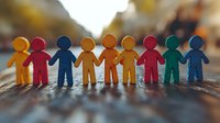 Colorful paper cutout figures holding hands in row symbolizing diversity, unity, and community support against blurred warm background. Suitable for social campaigns.