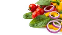 Fresh vegetables with cherry tomatoes, spinach leaves and colorful onion rings on white background for healthy cooking and meal preparation.