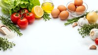 Fresh organic ingredients arranged on white background with eggs, tomatoes, herbs, lemon and olive oil for healthy cooking and meal preparation.