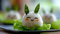 Cute rice ball character with lettuce ears on green salad leaf, kawaii style Japanese food art with happy smiling face, creative Asian cuisine presentation.