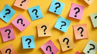 Colorful sticky notes with question marks scattered on yellow background for brainstorming, problem solving and decision making concepts.
