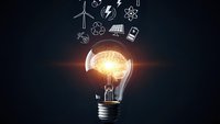 Glowing light bulb with brain inside surrounded by renewable energy icons on dark background representing innovation and sustainable technology solutions.